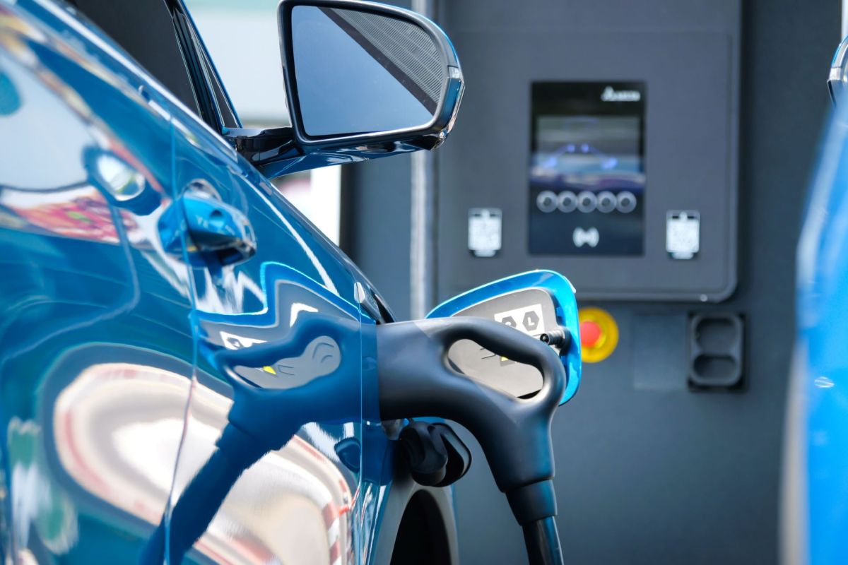 A close-up of a blue electric vehicle charging at a station with a digital display.