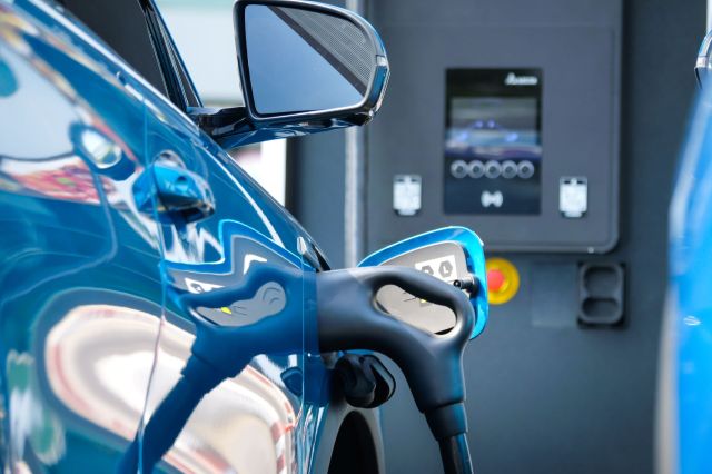 A close-up of a blue electric vehicle charging at a station with a digital display.
