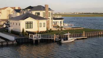 A modern waterfront house with a boat docked beside it.