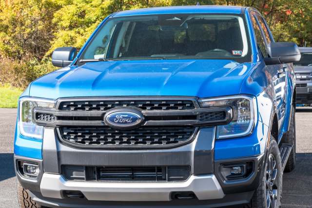 A front view of a blue Ford Ranger pickup truck parked in a scenic outdoor setting.