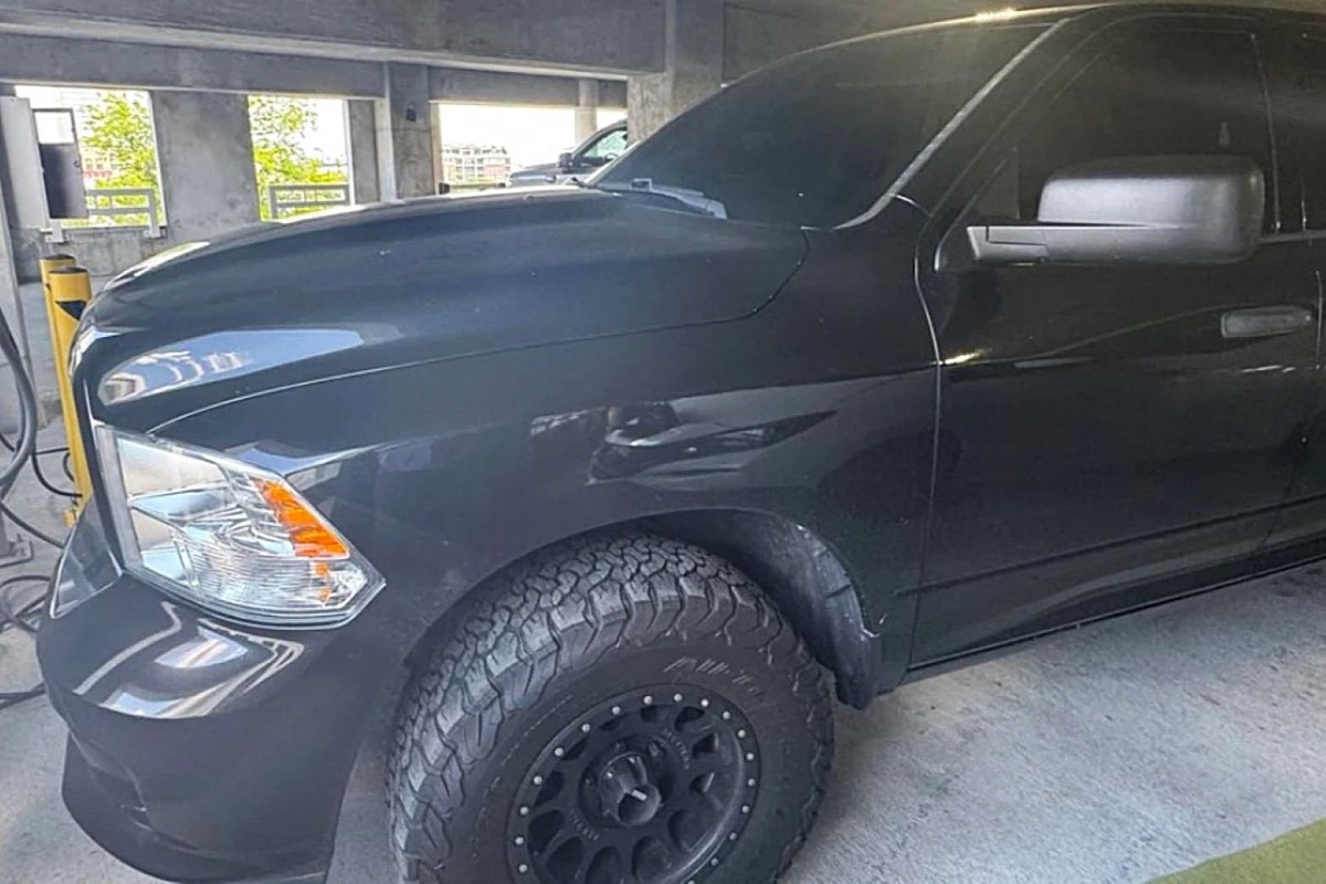 A black pickup truck parked in a concrete garage with visible rugged tires.
