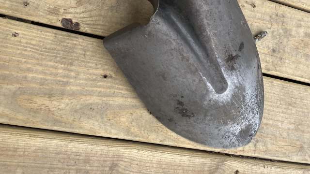 A metal shovel resting on weathered wooden planks.