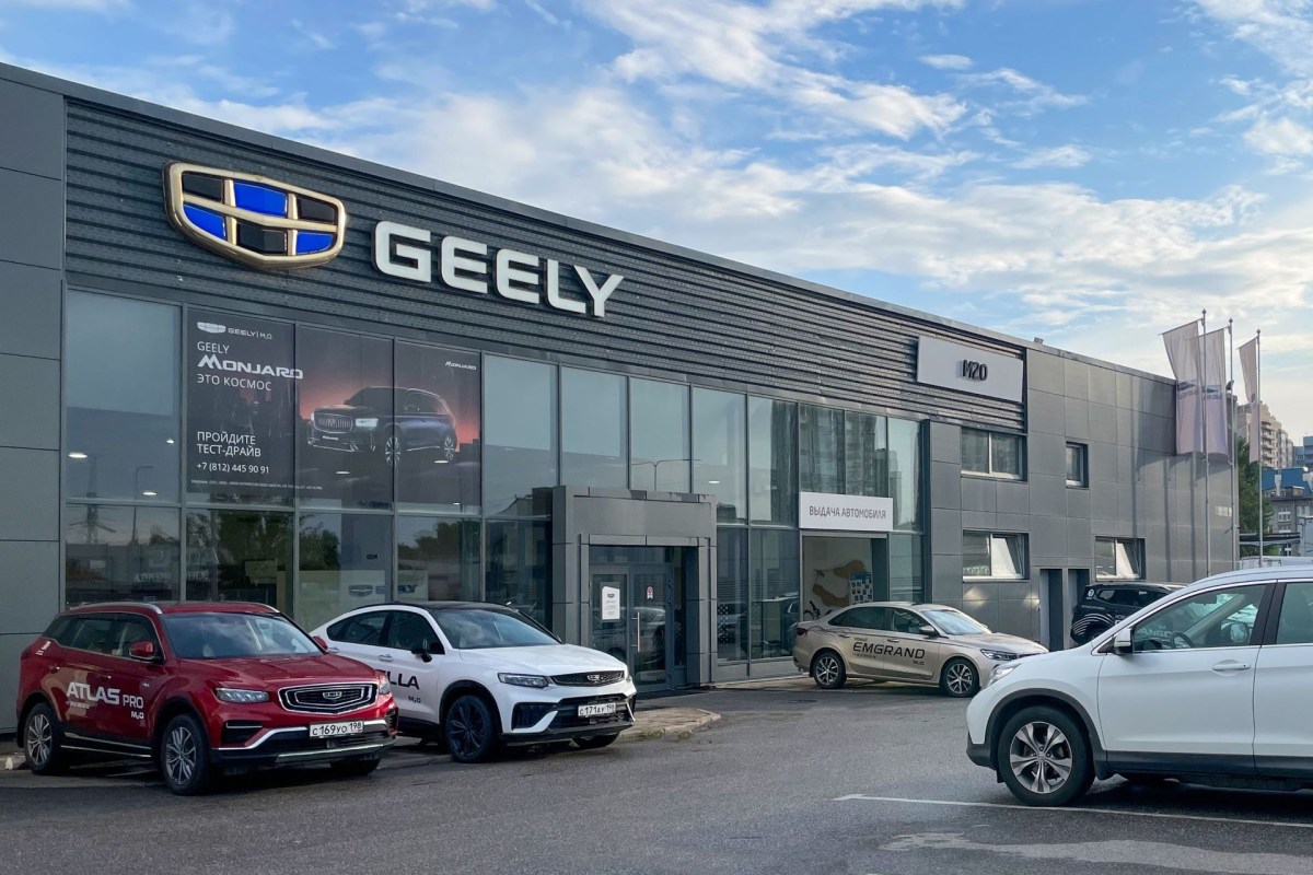 A Geely car dealership showcasing several parked vehicles and large windows displaying promotional signage.