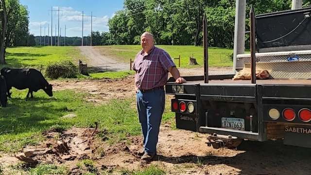 A farmer stands beside a truck.