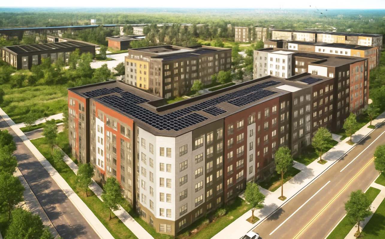 Aerial view of a modern apartment complex featuring solar panels, surrounded by green trees and pathways.