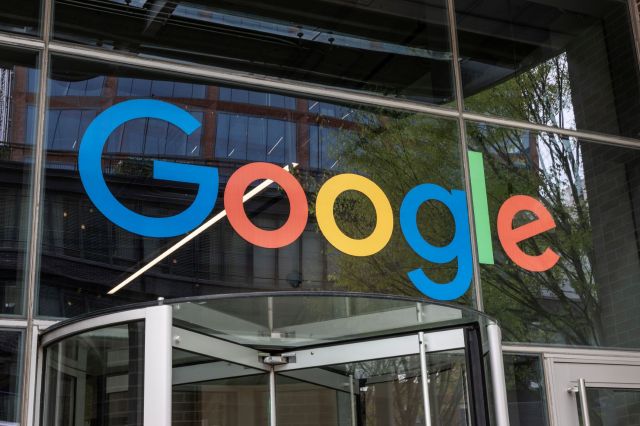 A close-up view of the Google logo displayed on the entrance of a modern building.