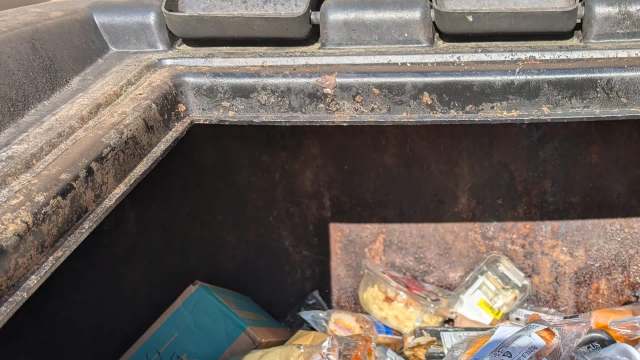 An open dumpster filled with discarded food packaging and waste.