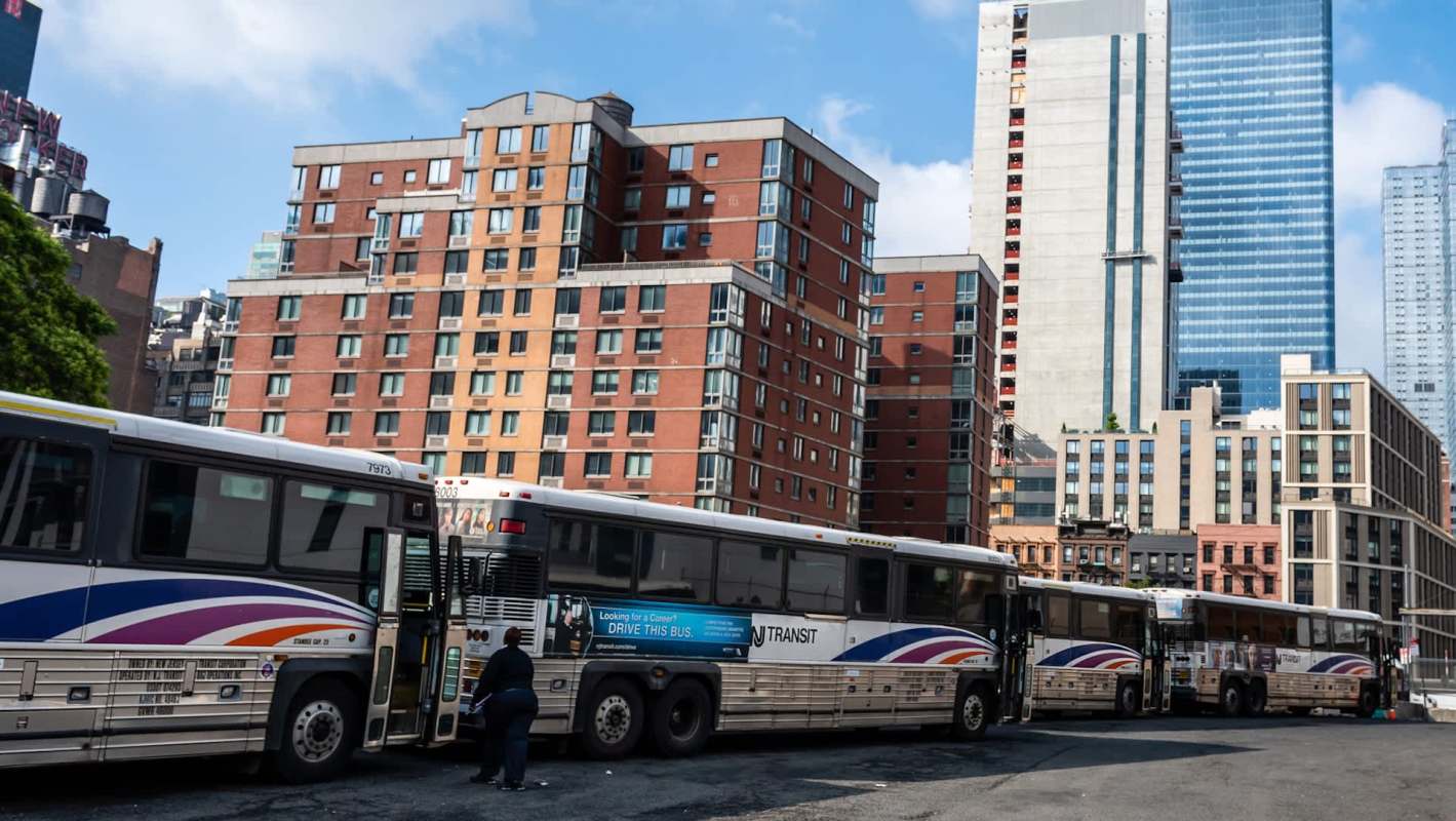 A row of parked buses in front of urban buildings.