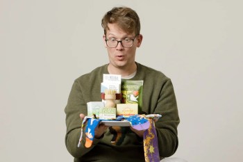 Hank Green holds a tray with eco-friendly products and colorful socks.