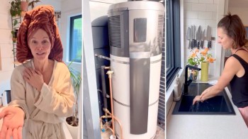 A woman in a robe with a towel on her head standing beside a hot water system and washes her hands at a sink.