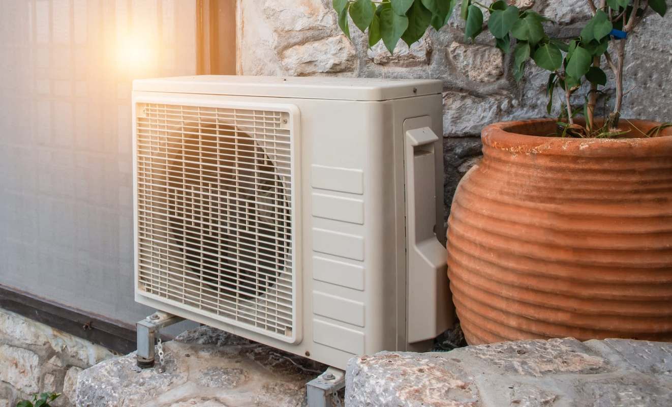 An outdoor air conditioning unit beside a large terracotta planter.