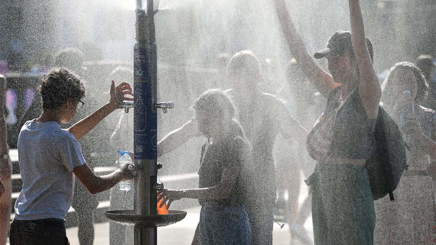 People playing in a public fountain on a sunny day.
