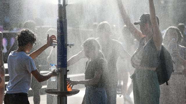 People playing in a public fountain on a sunny day.