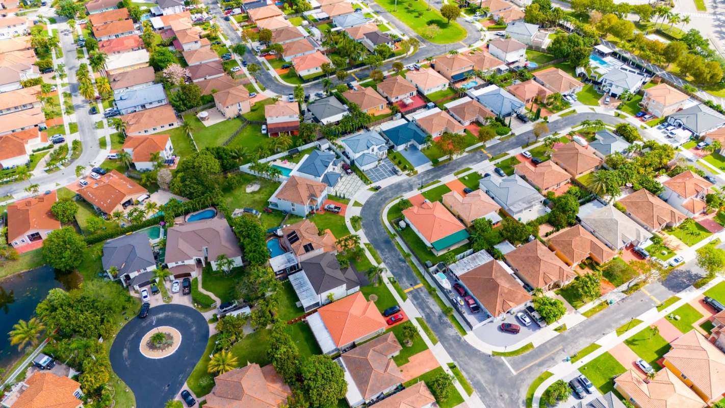 An aerial view of a suburban neighborhood featuring houses, gardens, and winding roads.