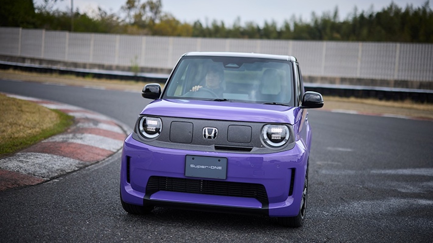 A vibrant purple car with distinctive headlights drives around a curved racetrack.