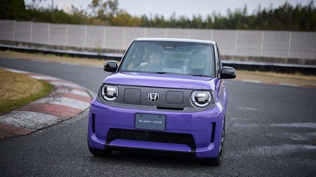 A vibrant purple car with distinctive headlights drives around a curved racetrack.