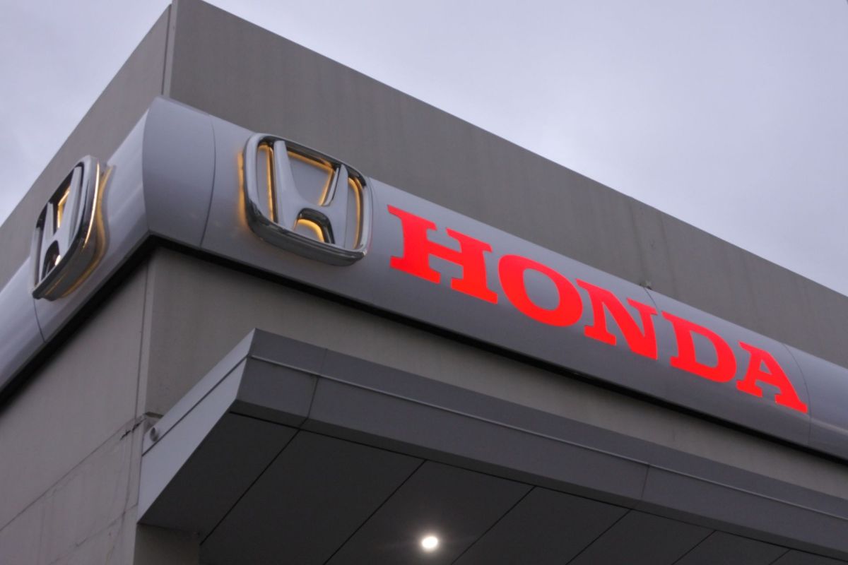 A close-up of a Honda dealership sign featuring the logo and the brand name in bright red letters.