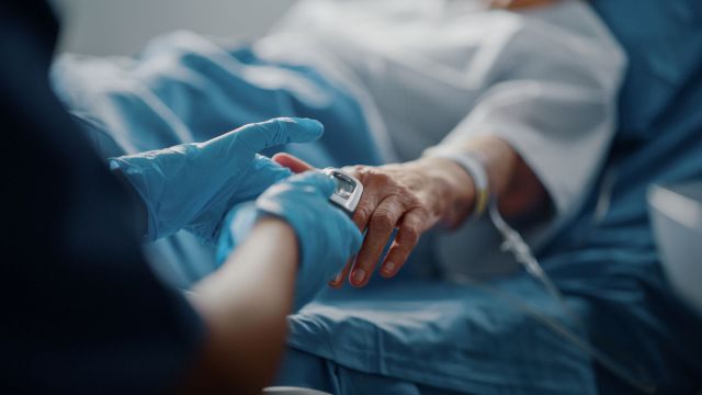 A healthcare professional checks a patient's pulse while holding their hand.