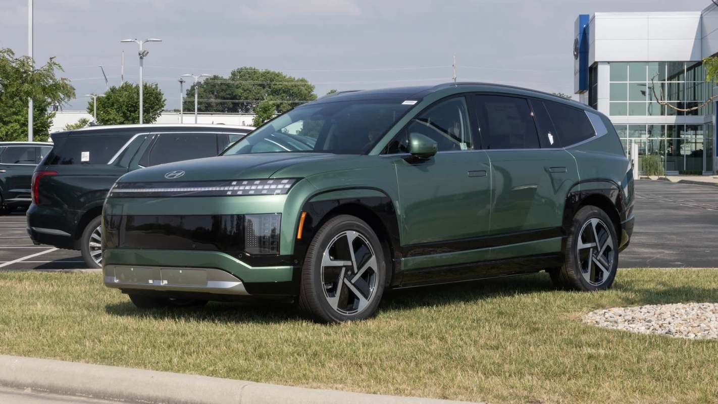 A green SUV parked on grass outside a Hyundai dealership.