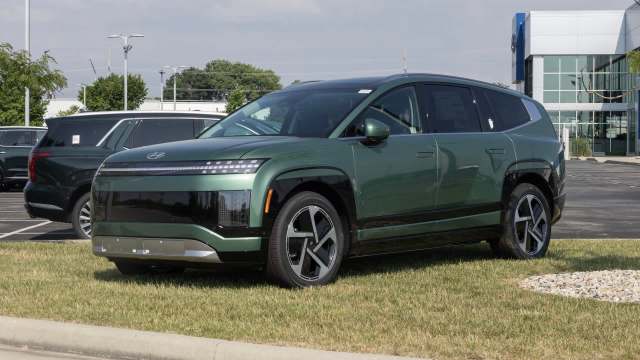 A green SUV parked on grass outside a Hyundai dealership.