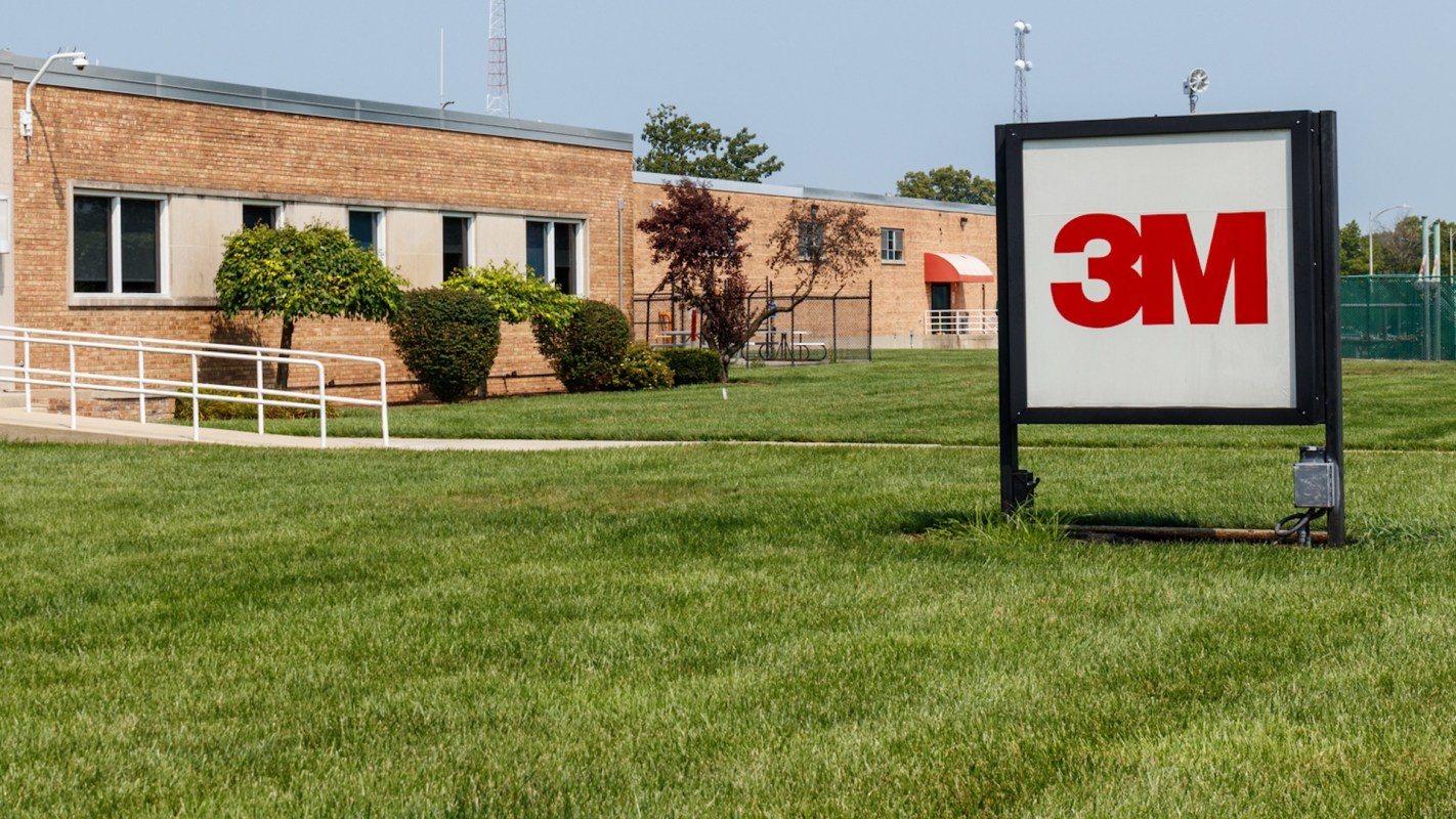 A green lawn with a prominent 3M sign in front of a brick building.