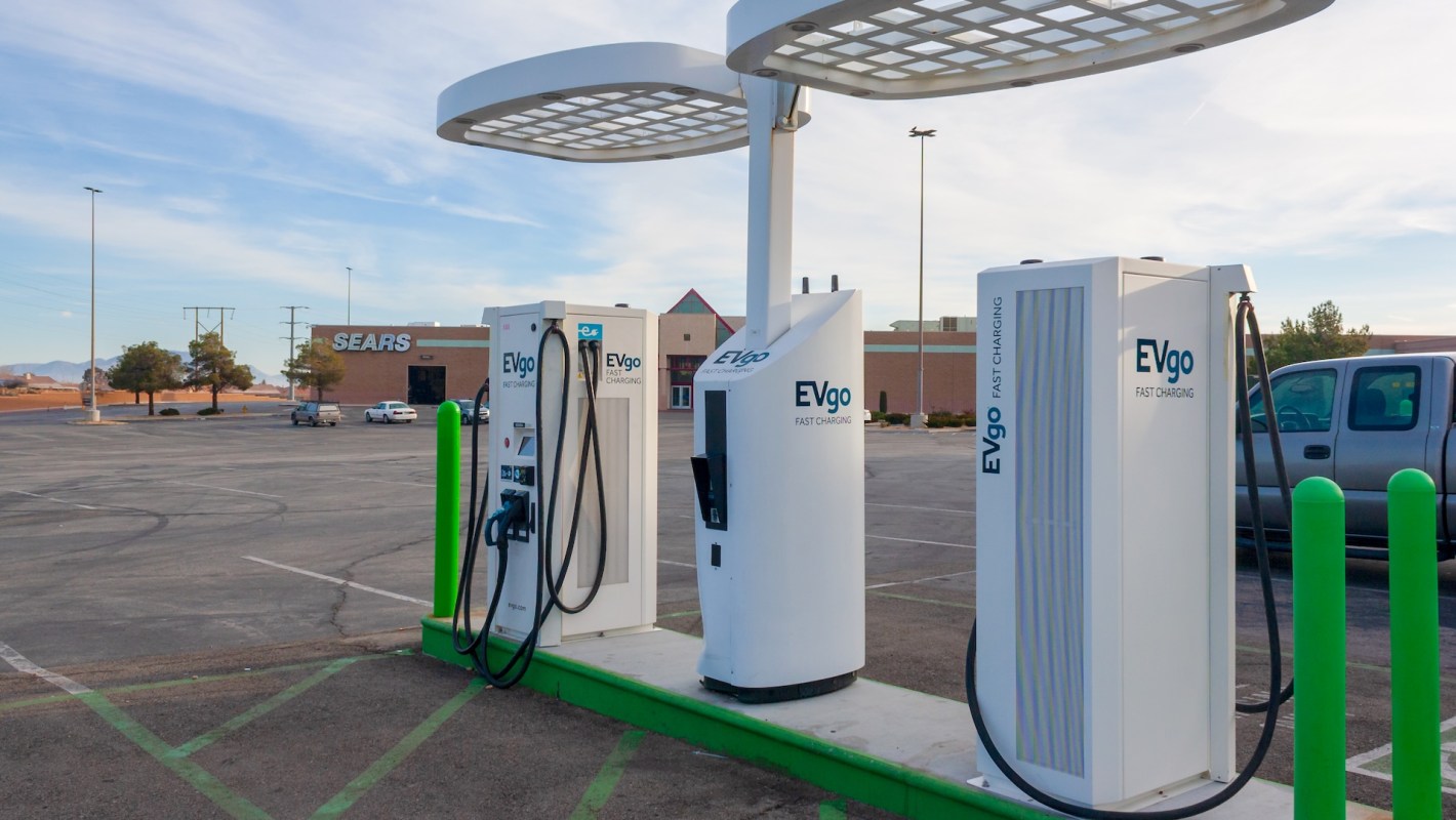 EVgo electric vehicle charging stations in a largely empty parking lot, with a Sears store in the background.