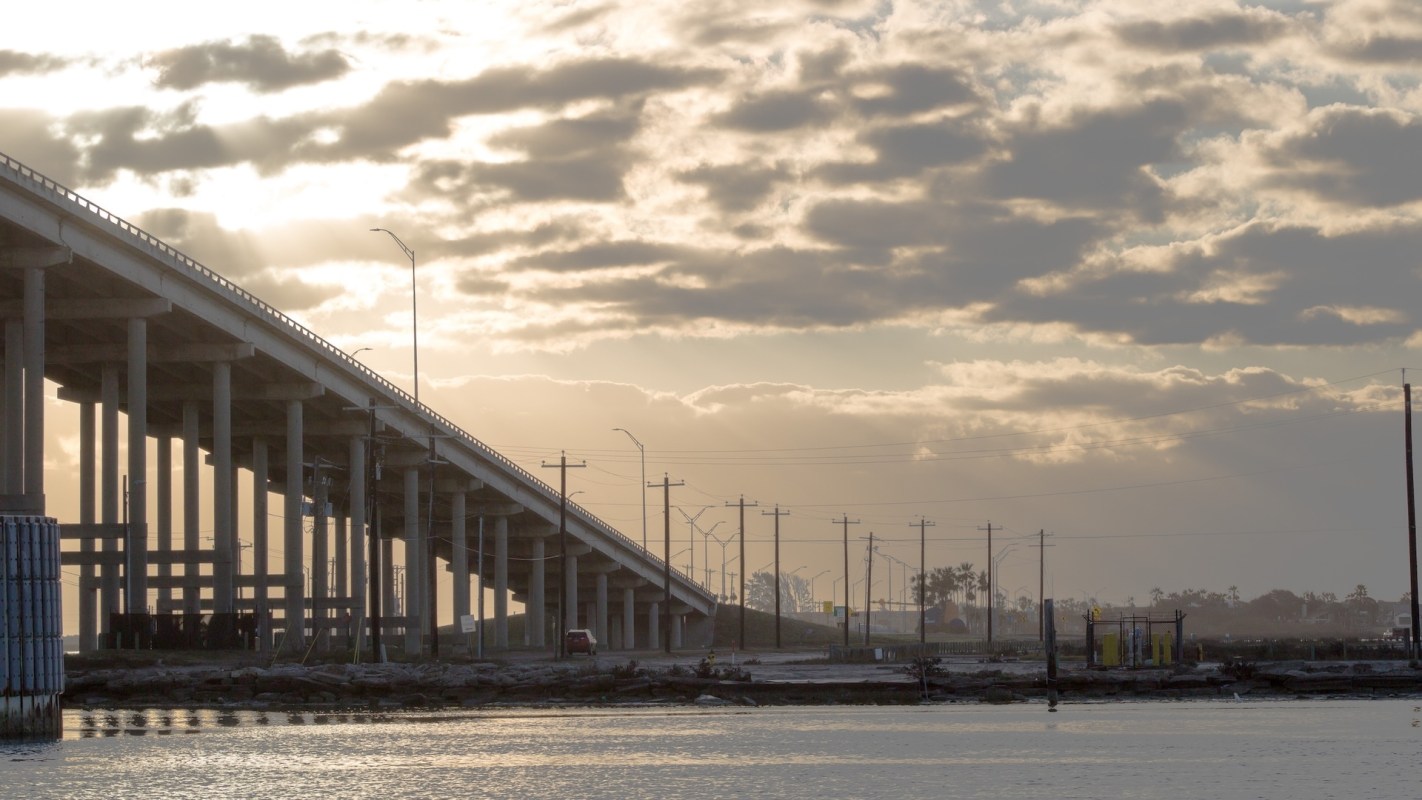A concrete bridge over a calm waterway during late afternoon.