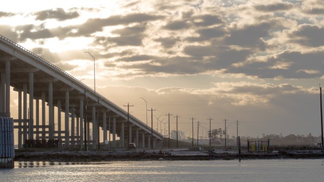 A concrete bridge over a calm waterway during late afternoon.