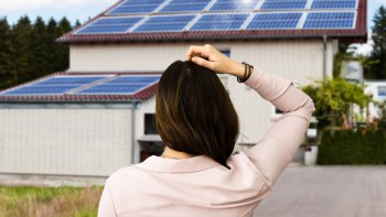A person looking at a house with solar panels.