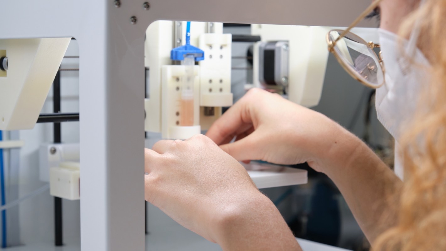 A person adjusting equipment inside a laboratory machine.