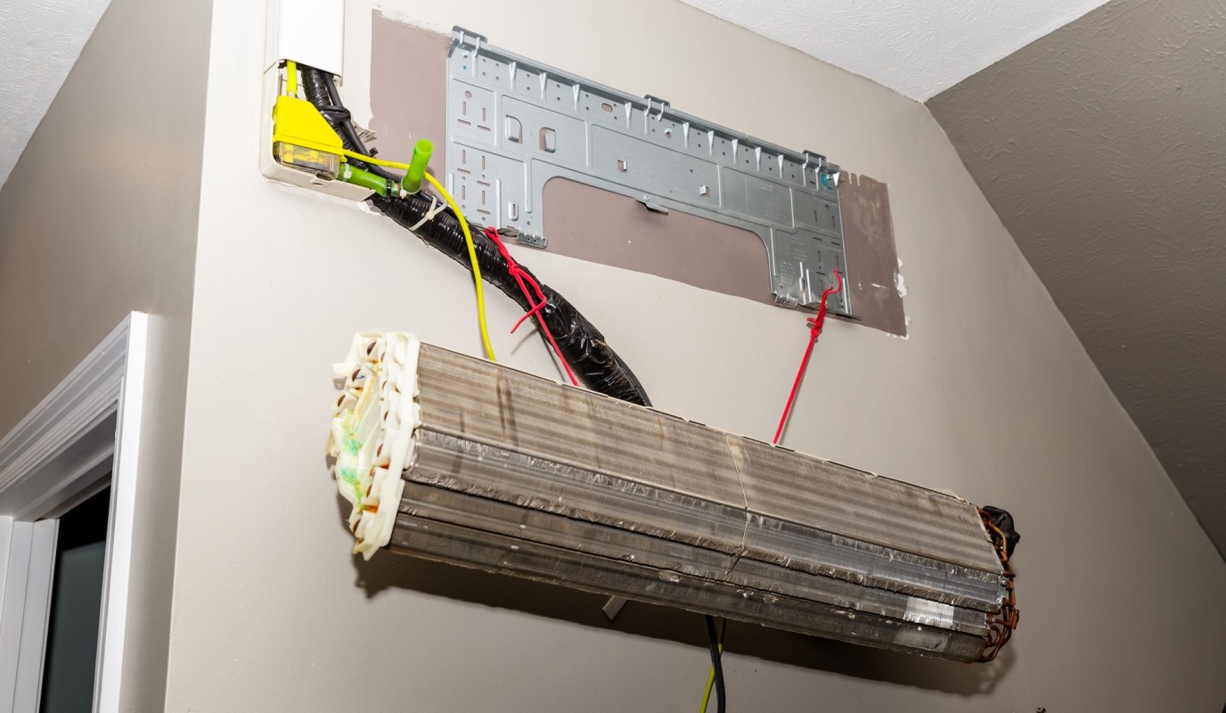 Exposed electrical wiring and components installed on a wall, with a metal mounting plate and a hanging unit.