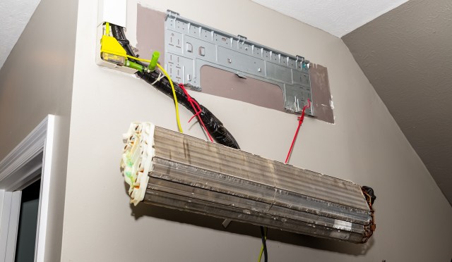 Exposed electrical wiring and components installed on a wall, with a metal mounting plate and a hanging unit.