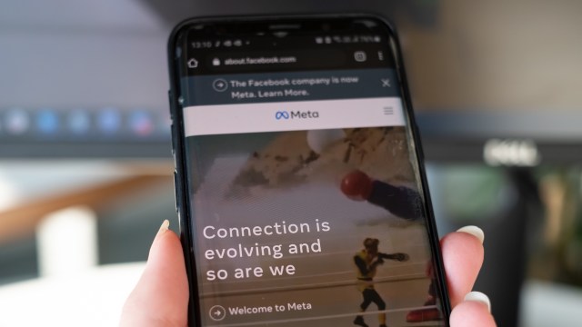 A close-up of a smartphone displaying a webpage about Meta, with a colorful image and text about evolving connections.