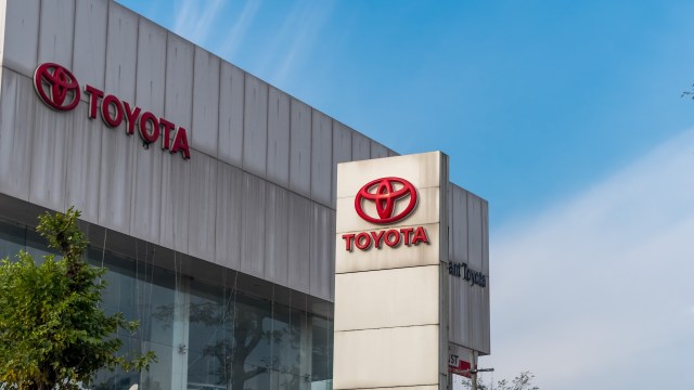 A Toyota dealership sign displayed outside a modern building against a clear blue sky.