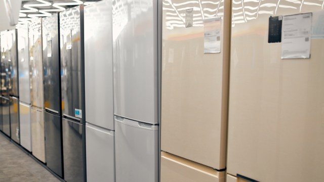 A row of various refrigerators in a store, featuring different colors and designs.