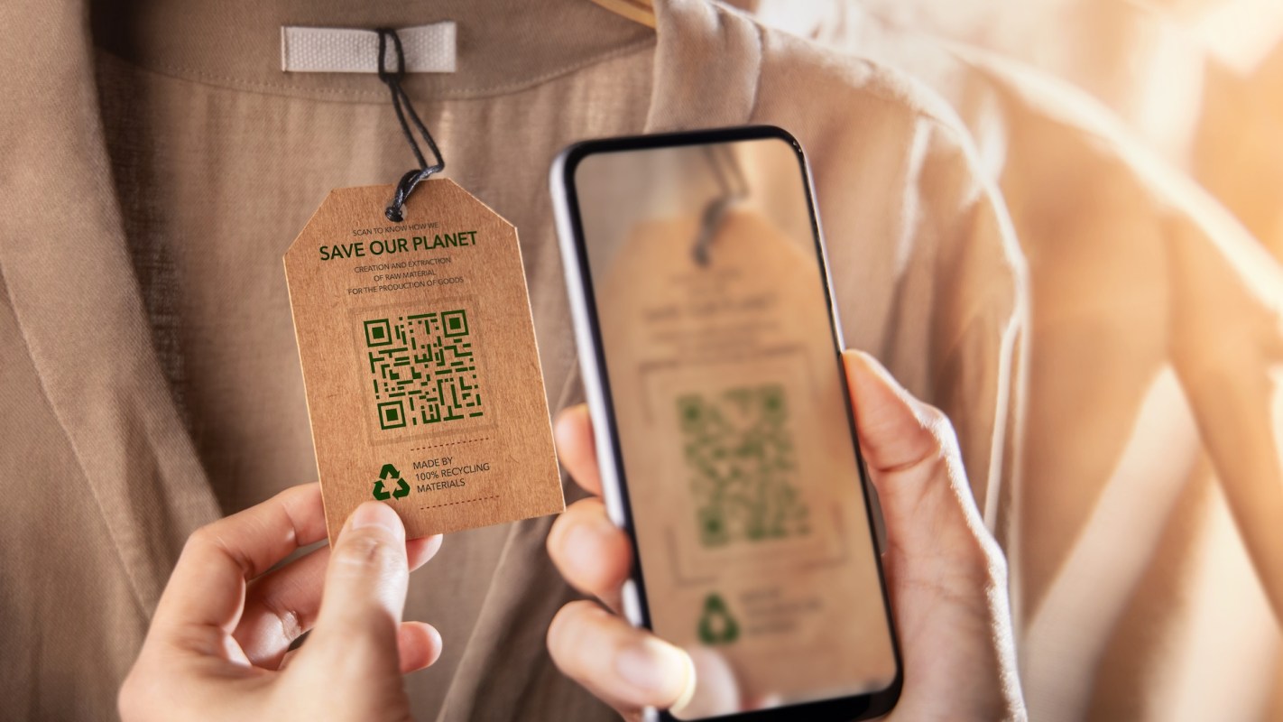 A person uses a smartphone to scan a clothing tag with a QR code.