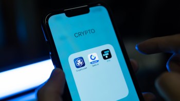 A close-up of a smartphone screen displaying a "Crypto" folder with three cryptocurrency app icons.