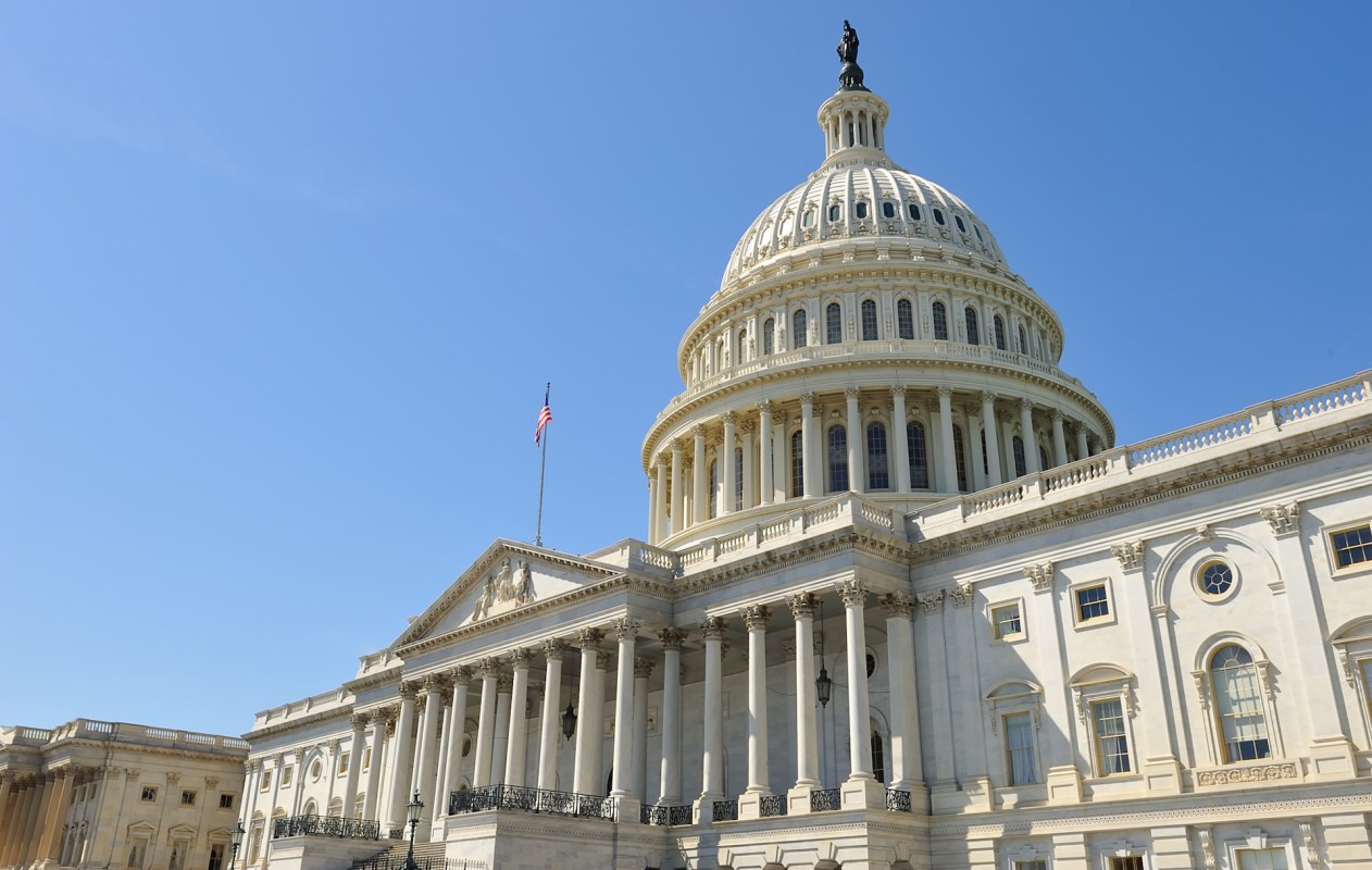 The U.S. Capitol building with its iconic dome and columns, set against a clear blue sky.