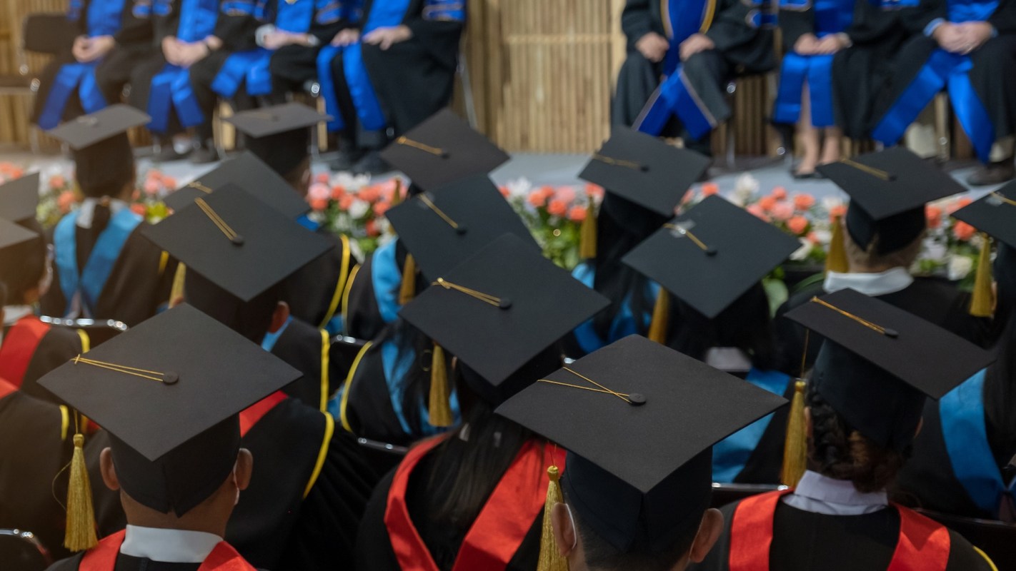 A crowd of students seated and wearing graduation attire.