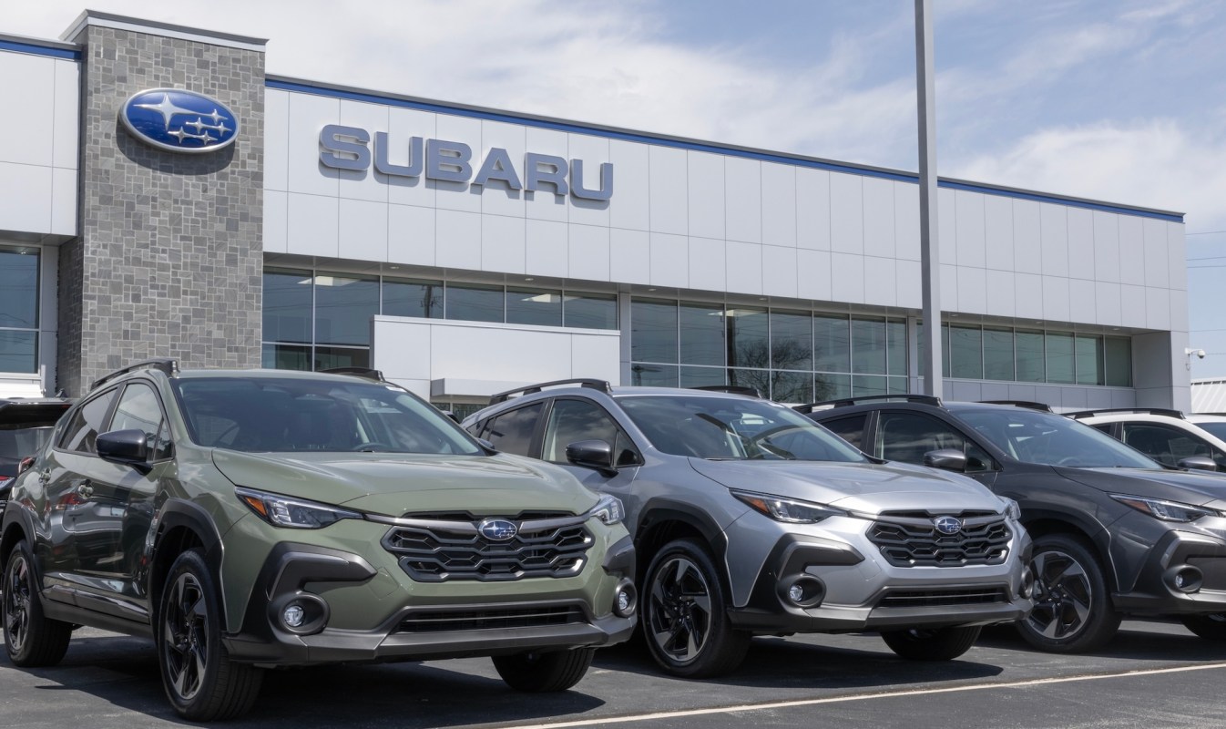 A row of Subaru vehicles in front of a dealership with a blue sky overhead.