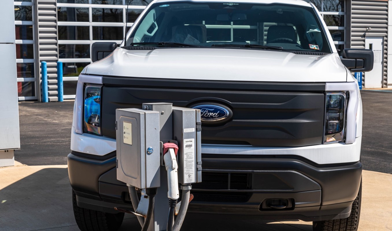 A white Ford electric pickup truck parked near a charging station.