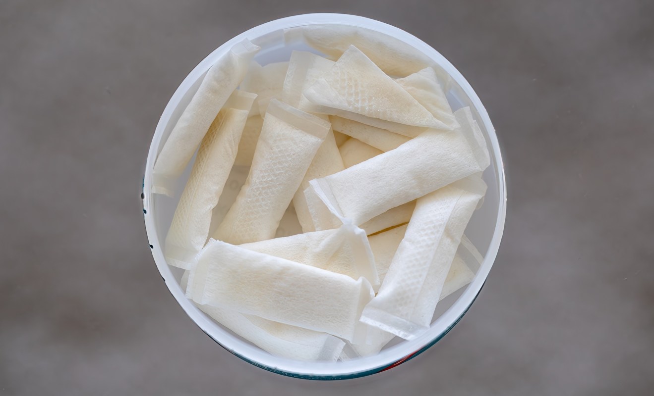 A container filled with individually wrapped pouches of a thin, white substance.