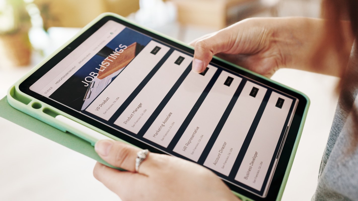 A person holding a tablet displaying a list of job listings and positions available.