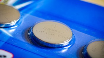 A close-up of CR2032 lithium coin batteries on a blue packaging background.