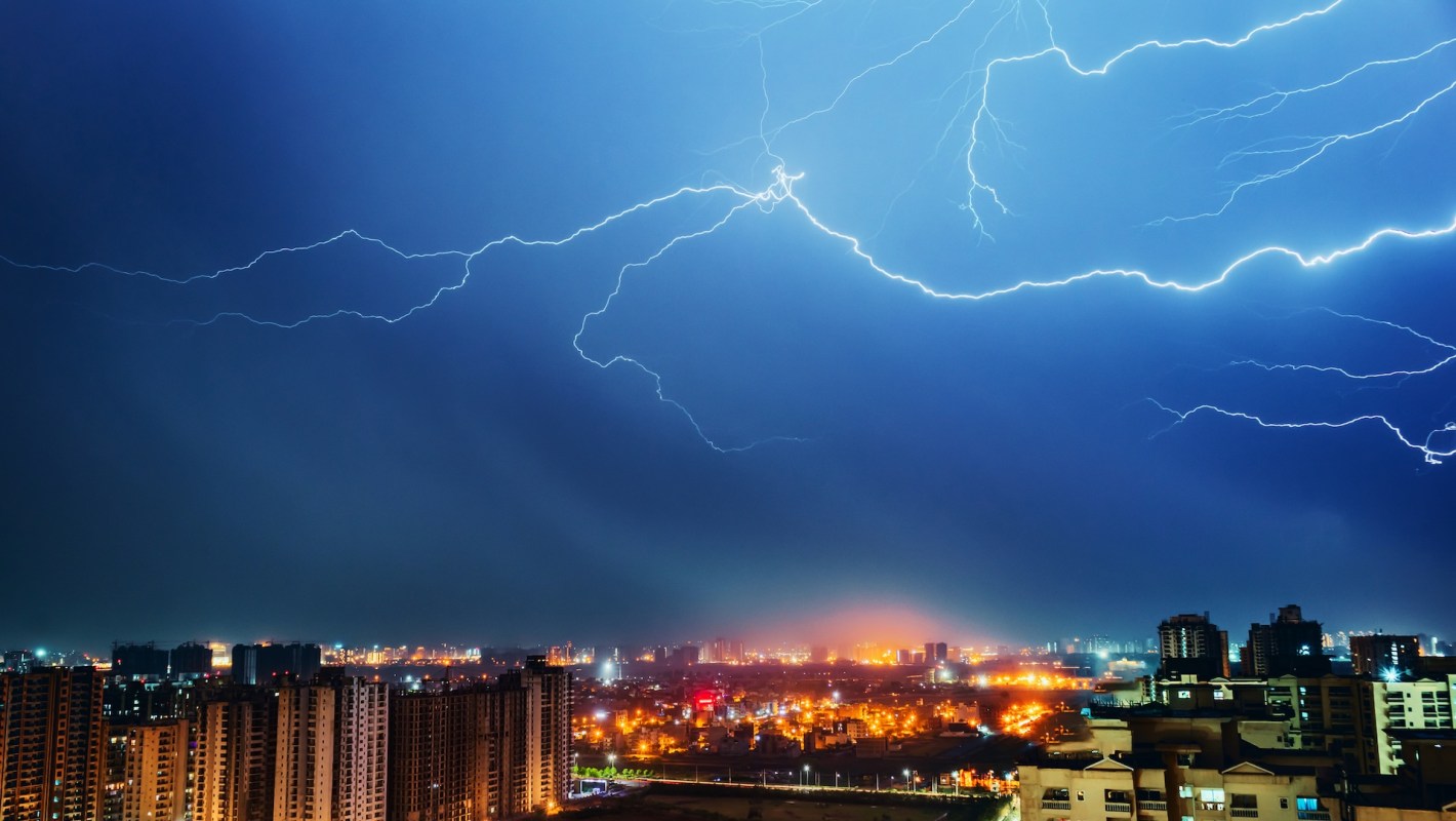 A dramatic lightning storm illuminates a city skyline at night.