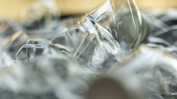 Close-up of crumpled, transparent plastic, reflecting light and creating an abstract visual effect.