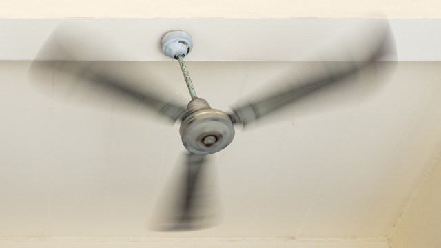 A ceiling fan spinning rapidly below a white ceiling.