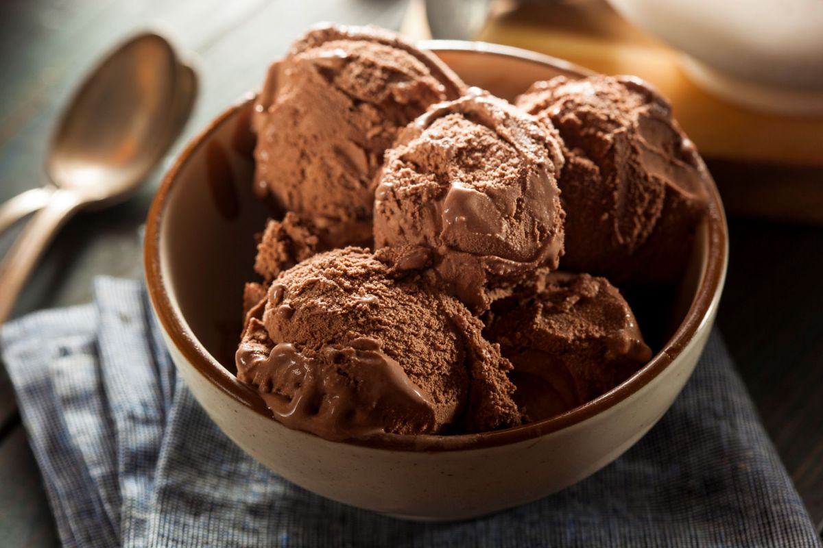 A bowl of rich chocolate ice cream scoops atop a blue checkered napkin.