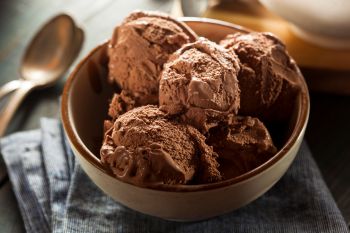 A bowl of rich chocolate ice cream scoops atop a blue checkered napkin.