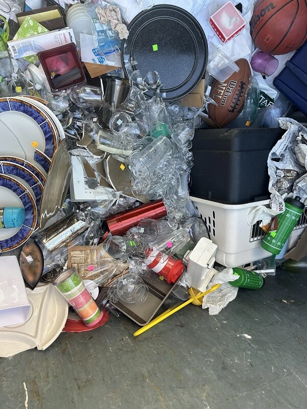 A pile of assorted discarded items including plastic cups, containers, and pieces of packaging on a floor.